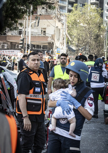 An Israeli medic carries a baby after an Iranian ballistic missile strike. An Iranian missile struck the main hospital in southern Israel early Thursday, causing extensive damage and wounding several people, though none seriously, according to the hospital. Other missiles hit a high-rise apartment building in Ramat Gan, and additional sites in central Israel, leaving at least 240 wounded and four of them seriously according to Israel's Health Ministry.