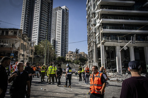 Israeli first responders seen near a building after an Iranian ballistic missile strike. An Iranian missile struck the main hospital in southern Israel early Thursday, causing extensive damage and wounding several people, though none seriously, according to the hospital. Other missiles hit a high-rise apartment building in Ramat Gan, and additional sites in central Israel, leaving at least 240 wounded and four of them seriously according to Israel's Health Ministry.