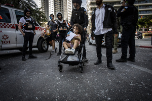 A police officer evacuates a toddler after an Iranian ballistic missile strike. An Iranian missile struck the main hospital in southern Israel early Thursday, causing extensive damage and wounding several people, though none seriously, according to the hospital. Other missiles hit a high-rise apartment building in Ramat Gan, and additional sites in central Israel, leaving at least 240 wounded and four of them seriously according to Israel's Health Ministry.