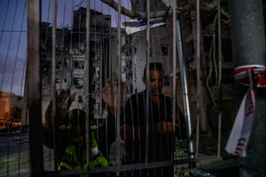 Municipality worker seen on a gate of a residential building in Be’er Sheva destroyed by an Iranian ballistic missile, in which four Israelis were killed.