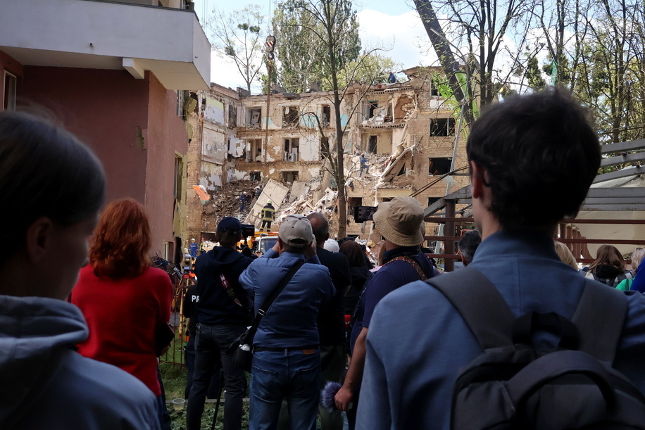 People look at a damaged building where a search operation is conducted after shelling during the Russian invasion. Russia has launched its latest missile and drone strike killing at least nine people as Moscow steps up airstrikes on civilian infrastructure.