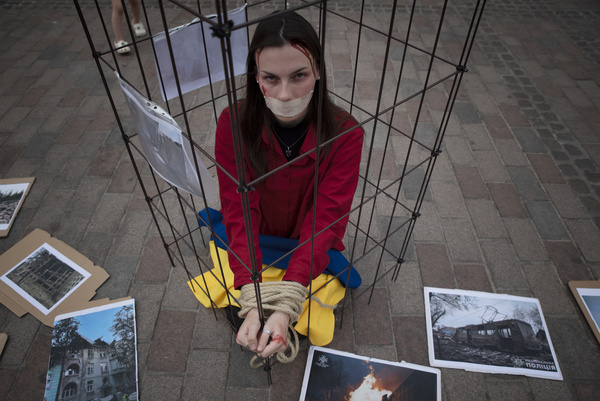 A girl sits locked in a cage with her hands tied and her mouth gagged during the protest. An action in support of Ukraine was held in Gdansk on Dluga Street. The event was intended as a reminder that the war in Ukraine is still going on, cities are being shelled and people, including children, are dying. Participants brought flags and posters with them. The event was a performance.