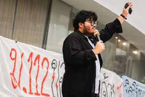 A speaker addresses the crowd during a “People’s Amnesty” vigil in Bangkok. People gathered outside Bangkok Art and Culture Centre for a candlelight vigil titled “Light Up Hope for the People’s Amnesty.” Organized ahead of a parliamentary debate on the 16 July 2025, the event featured personal testimonies, portraits of 50 political detainees, and a red rose display reading “Amnesty 112.” Participants called for the passage of a comprehensive amnesty bill covering cases under Section 112 of the Thai Criminal Code.