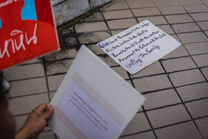 A handwritten sign lies on the ground during the “People’s Amnesty” vigil. People gathered outside Bangkok Art and Culture Centre for a candlelight vigil titled “Light Up Hope for the People’s Amnesty.” Organized ahead of a parliamentary debate on the 16 July 2025, the event featured personal testimonies, portraits of 50 political detainees, and a red rose display reading “Amnesty 112.” Participants called for the passage of a comprehensive amnesty bill covering cases under Section 112 of the Thai Criminal Code.
