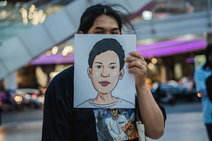 A protester holds up an illustrated portrait of a detained activist during the “People’s Amnesty” vigil. People gathered outside Bangkok Art and Culture Centre for a candlelight vigil titled “Light Up Hope for the People’s Amnesty.” Organized ahead of a parliamentary debate on the 16 July 2025, the event featured personal testimonies, portraits of 50 political detainees, and a red rose display reading “Amnesty 112.” Participants called for the passage of a comprehensive amnesty bill covering cases under Section 112 of the Thai Criminal Code.