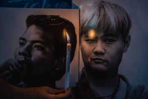 A candle is held in front of portraits of detained activists during a vigil. People gathered outside Bangkok Art and Culture Centre for a candlelight vigil titled “Light Up Hope for the People’s Amnesty.” Organized ahead of a parliamentary debate on the 16 July 2025, the event featured personal testimonies, portraits of 50 political detainees, and a red rose display reading “Amnesty 112.” Participants called for the passage of a comprehensive amnesty bill covering cases under Section 112 of the Thai Criminal Code.