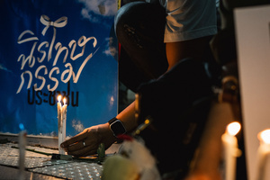 A participant lights candles in front of a banner reading “People’s Amnesty” during the vigil. People gathered outside Bangkok Art and Culture Centre for a candlelight vigil titled “Light Up Hope for the People’s Amnesty.” Organized ahead of a parliamentary debate on the 16 July 2025, the event featured personal testimonies, portraits of 50 political detainees, and a red rose display reading “Amnesty 112.” Participants called for the passage of a comprehensive amnesty bill covering cases under Section 112 of the Thai Criminal Code.