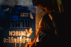 A man kneels beside candlelight during the “People’s Amnesty” vigil. The sign behind him reads: “If passed, they will be able to return home,” referring to the proposed amnesty bill for political detainees. People gathered outside Bangkok Art and Culture Centre for a candlelight vigil titled “Light Up Hope for the People’s Amnesty.” Organized ahead of a parliamentary debate on the 16 July 2025, the event featured personal testimonies, portraits of 50 political detainees, and a red rose display reading “Amnesty 112.” Participants called for the passage of a comprehensive amnesty bill covering cases under Section 112 of the Thai Criminal Code.
