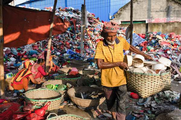 A worker seen carrying a bucket of sorted plastic material to store in the yard for recycle at the plastic recycle factory. Plastic recycling factories are becoming another growing business, seeing their high demand in various kind of materials from cloths to different kind of goods. People believe its another way to save our environment.