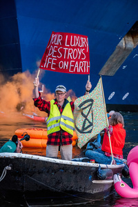 Extinction Rebellion activist holds a placard, expressing his opinion during an attempt to block the path of Luxury Ocean liner the "Celebrity Eclipse" from docking at the Passages Terminal. A little before sunrise, climate activists from Extinction Rebellion, Netherlands attempted to block the path of Luxury Ocean liner the ‘Celebrity Eclipse’ from docking at the Passages Terminal in Amsterdam. The ‘Celebrity Eclipse’ is operated by Celebrity Cruises, a subsidiary of Royal Caribbean Group. The activists numbered 30 in all, with the majority in 2-person kayaks stating that "Cruise ships are floating environmental disasters. They should not be allowed in Dutch waters. We demand strict and binding national and international environmental standards and regulations, as well as strict enforcement and sanctions policy."