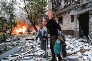 A man assists an elderly resident in evacuating from her damaged home following the Russian missile attack. On July 31, 2025, a massive Russian missile and drone attack on Kyiv left at least 16 people dead, including two children, and caused widespread destruction. Ukrainian forces intercepted most of the 309 drones and eight cruise missiles, but some struck residential areas, collapsing a section of a nine-story building. Over 100 buildings were damaged across 27 locations, including schools, hospitals, and homes.