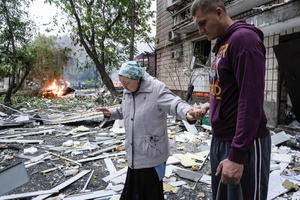 A man assists an elderly resident in evacuating from her damaged home following the Russian missile attack. On July 31, 2025, a massive Russian missile and drone attack on Kyiv left at least 16 people dead, including two children, and caused widespread destruction. Ukrainian forces intercepted most of the 309 drones and eight cruise missiles, but some struck residential areas, collapsing a section of a nine-story building. Over 100 buildings were damaged across 27 locations, including schools, hospitals, and homes.