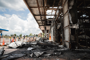Charred debris and burnt structures outside the destroyed 7-Eleven at a PTT station in Kantharalak, weeks after the Thai-Cambodian border clash rocket strike. Three weeks after the Cambodian border clash, Kantharalak still bears the scars, including the July 24 rocket strike on a PTT station that killed eight civilians and injured several others. The station remains closed, leaving more than 50 employees in limbo as compensation issues remain unresolved.