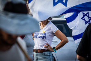 An Israeli woman seen between Israeli flags while at the main costal Highway near Beit Yanai. Demonstrators call on Israeli Prime Minister Benjamin Netanyahu to end the war in Gaza and to release all 50 Israeli hostages held by Hamas since October 7, 2023. On what was the biggest day of national mobilization, hundreds of thousands of people poured into the streets around the country to demand a Hostage release deal and an end to the war in Gaza.