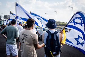 Israelis hold the Israeli flag as they block the main costal Highway near Beit Yanai. Demonstrators call on Israeli Prime Minister Benjamin Netanyahu to end the war in Gaza and to release all 50 Israeli hostages held by Hamas since October 7, 2023. On what was the biggest day of national mobilization, hundreds of thousands of people poured into the streets around the country to demand a Hostage release deal and an end to the war in Gaza.