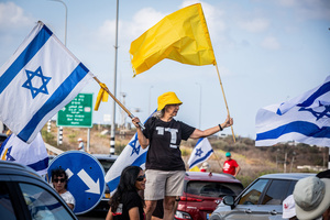 Israelis hold the Israeli flag as they block the main costal Highway near Beit Yanai. Demonstrators call on Israeli Prime Minister Benjamin Netanyahu to end the war in Gaza and to release all 50 Israeli hostages held by Hamas since October 7, 2023. On what was the biggest day of national mobilization, hundreds of thousands of people poured into the streets around the country to demand a Hostage release deal and an end to the war in Gaza.