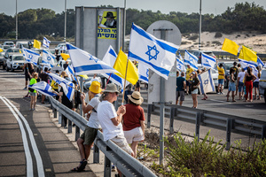 Israelis hold the Israeli flag as they block the main costal Highway near Beit Yanai. Demonstrators call on Israeli Prime Minister Benjamin Netanyahu to end the war in Gaza and to release all 50 Israeli hostages held by Hamas since October 7, 2023. On what was the biggest day of national mobilization, hundreds of thousands of people poured into the streets around the country to demand a Hostage release deal and an end to the war in Gaza.
