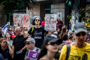 A protester holds up signs during a demonstration. Demonstrators call on Israeli Prime Minister Benjamin Netanyahu to end the war in Gaza and to release all 50 Israeli hostages held by Hamas since October 7, 2023. On what was the biggest day of national mobilization, hundreds of thousands of people poured into the streets around the country to demand a Hostage release deal and an end to the war in Gaza.