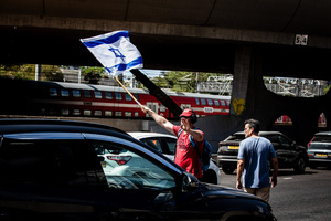 A protester waves the Israeli flag as he tries to block the Ayalon Highway during a demonstration. Demonstrators call on Israeli Prime Minister Benjamin Netanyahu to end the war in Gaza and to release all 50 Israeli hostages held by Hamas since October 7, 2023. On what was the biggest day of national mobilization, hundreds of thousands of people poured into the streets around the country to demand a Hostage release deal and an end to the war in Gaza.