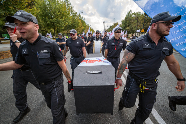 Prison officers carry a mock coffin labelled with the name of the Prison Service during the rally. On Tuesday afternoon, officers within the Polish prison service gathered at the Chancellery of the Prime Minister of Poland to protest against poor working conditions and payments. Protesters marched with placards, banners, and flags from the chancellery to the Justice Department building, then headed to the Polish Parliament. The leaders of the protest believed that, the lack of increase in payments causes shortages, which in turn leads to an overload of responsibilities and less safety.