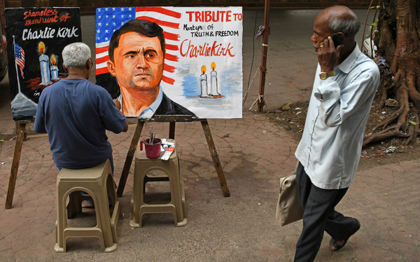 A teacher from Gurukul school of art paints a poster paying tribute to US political activist and author Charlie Kirk as a man talking on his mobile phone walks past outside the art school. Gurukul school of art pays tribute to 31 years old Charlie Kirk, a U.S political activist, author and a close ally of President Donald Trump who was shot dead when he was speaking to a large crowd at an event at Utah Valley university.