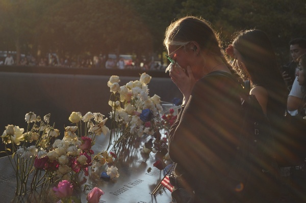 A person sheds tears while paying tribute at the September 11 memorial pool. On the 24th anniversary of the September 11, 2001 terrorist attacks, people gathered in downtown Manhattan, New York City to pay tribute to those lost on 9/11. People visited the memorial pools at Ground Zero of the World Trade Center, planting flowers and photos of loved ones who perished on 9/11.