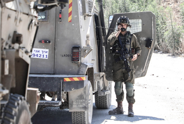 An Israeli soldier speaks on the phone from inside a military vehicle near the site of an explosive device in the city of Tulkarm, in the northern West Bank. The explosion injured two Israeli soldiers, prompting the army to impose a siege on the city.