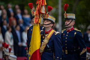 Uniformed officers hold a Spanish flag. During the Armed Forces parade on National Day led by King Felipe VI, Queen Letizia, their daughters Leonor de Borbón, Princess of Asturias and Infanta Sofía de Borbón.