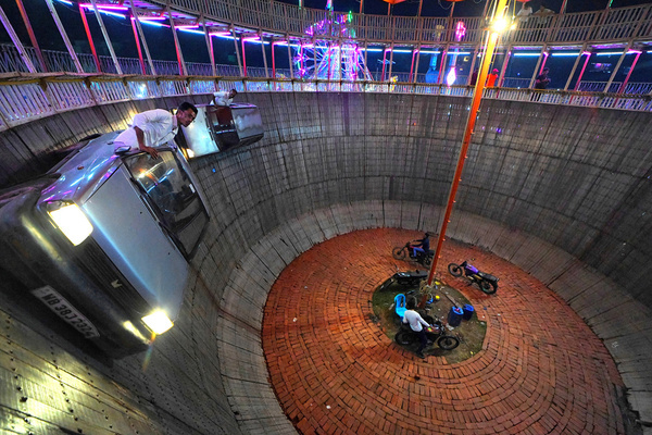 Stuntman Babar Khan hangs out of the window of a car he steers it in the Well of Death, locally known as Maut ka kuaan at a Mela (Fair) ground. This well or bowl - also known as a wall of death, is about 30 feet deep and made from wooden planks, supported from the outside.