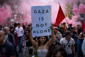 A pro-Palestinian protester carries a placard reading "Gaza is not alone" during the demonstration. A nationwide strike was held all over Spain, with demonstration in all the main cities. More than 20.000 of pro-Palestinian protesters marched in Barcelona, with several clashes with police and episodes of looting and burning of dumpsters.