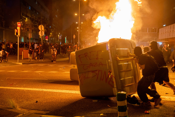 Protesters push a burning container during the riots in front of the Israeli consulate. A demonstration linked to the general strike in support of Palestine ended in violent clashes outside the Israeli consulate. Protesters burned containers and threw stones, prompting police to respond with force, using heavy charges and pepper spray to disperse the crowd.