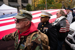 Veterans of the United States Armed Forces march while holding a large American flag during the 106th annual Veterans Day Parade.