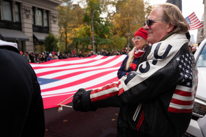 Veterans of the United States Armed Forces march while holding a large American flag during the 106th annual Veterans Day Parade.