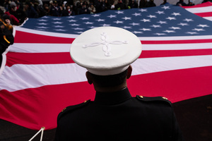 A U.S. Marine in dress uniform holds part of a large American flag during the 106th annual Veterans Day Parade.