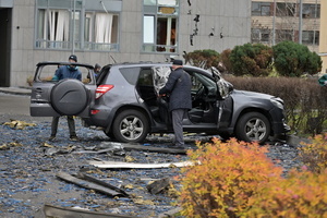 A man inspects a damaged car in a yard of an apartment building damaged by a Russian strike.