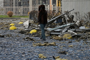 A woman stands in the rubble in the courtyard of an apartment building damaged by a Russian strike.