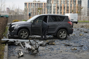 A man inspects a damaged car in a yard of an apartment building damaged by a Russian strike.
