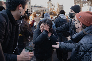 A woman washes pepper spray from her face as Immigration and Customs Enforcement (ICE) agents are confronted by protestors during an attempted sweep on Canal Street in Manhattan. ICE has cracked down on vendors selling counterfit goods in New York City.