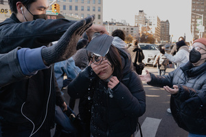 A woman washes pepper spray from her face as Immigration and Customs Enforcement (ICE) agents are confronted by protestors during an attempted sweep on Canal Street in Manhattan. ICE has cracked down on vendors selling counterfit goods in New York City.