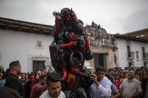 Neighbors carry the paper figure known as "The Three Wise Devils" to be burned, during the Burning of the Devil in Antigua Guatemala, on the eve of the celebration of the Virgin of the Immaculate Conception, festivities that mark the beginning of Christmas.