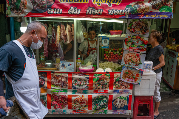 A porter walks past a food stall at Pratunam Market, one of the largest and busiest wholesale clothing markets in Bangkok.