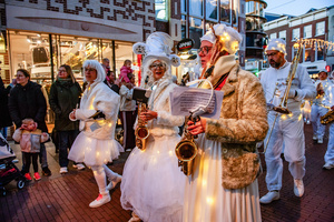 A music band is seen performing while wearing white costumes with lights. The Winter Wonder Parade marks the festive opening of the annual Nijmegen Winter Weeks. This enchanting spectacle features a fairytale procession including a winter carriage pulled by white horses, ice queens on stilts, musicians, dancers, and jugglers. The parade departs from the Lindenberg at 4:30 PM and concludes at the Grote Markt, where the Christmas tree lighting officially starts three weeks of winter magic.