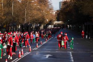 A family dressed in Christmas attire walks down a street against the flow of traffic during a charity race. A charity race was organized by the Spanish department store chain El Corte Ingles where participants, mostly families, run dressed as Santa Claus or in Christmas-themed costumes.