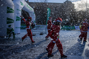 A group of participants in a charity race reach the finish line. A charity race was organized by the Spanish department store chain El Corte Ingles where participants, mostly families, run dressed as Santa Claus or in Christmas-themed costumes.