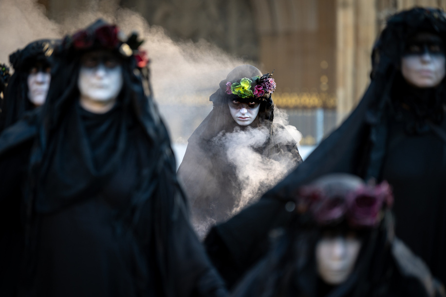 An oil slicker seen in a portrait. Extinction Rebellion Oil Slickers staged a symbolic performance protest in Whitehall moving in formation and stopping at Parliament Square, the Ministry of Defence, and 55 Tufton Street to highlight what they describe as government failure to meet climate commitments. They carried banners reading “Tell the Truth”, “A Better World Is Possible” and “1.5°C Is Dead”.