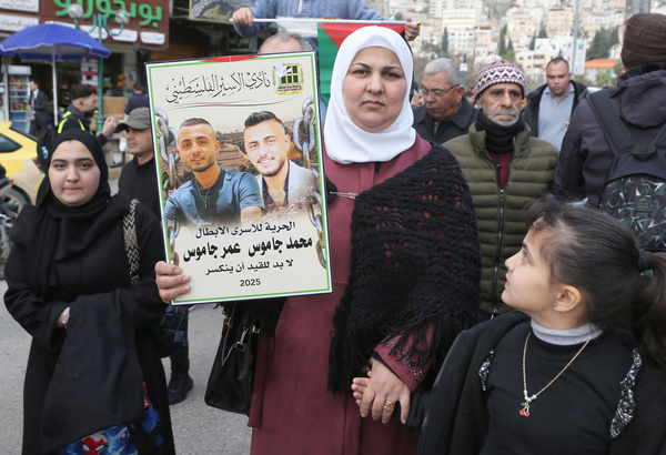 A Palestinian woman seen raising a picture of her family members that were imprisoned in Israeli jails . Palestinians blocked the streets during a protest against the freezing of their sons' salaries, demanding that the Palestinian Authority resume their payments.
