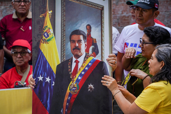 A demonstrator holds a portrait of Nicolas Maduro during a protest in support of the Venezuelan president following reports of his apprehension by U.S. military forces in Caracas.