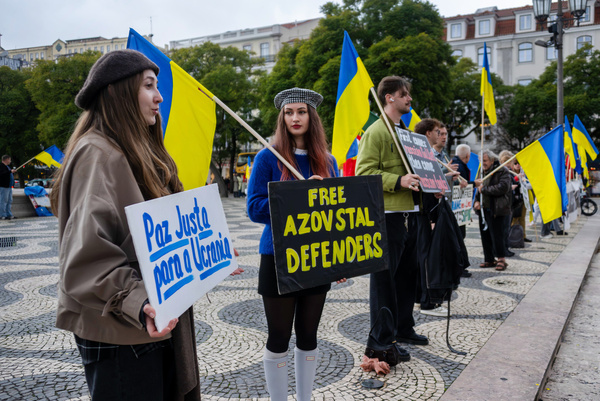 Protesters are seen holding placards and flags during a protest in support of Ukrainian people. The conflict in Ukraine has escalated again in recent days, while security advisors from several countries met in Kyiv to advance an international peace plan. Russia has also announced a new policy of permanent conscription starting in 2026, reinforcing the country's militarization. Meanwhile, a survey revealed that 76% of Ukrainians reject any agreement that involves ceding occupied territories to Russia, showing that society remains steadfast despite the wear and tear of war.