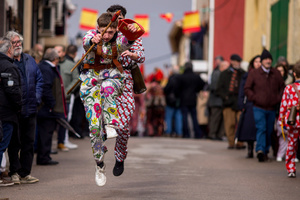 A member of the Endiablada brotherhood, wearing cowbells on his waist and the traditional costume, jumps with his arms in the procession of the image of Saint Blaise, during the festival of La Endiablada in Almonacid del Marquesado. Celebrated in honor of the Virgin of Candelaria and Saint Blaise of Sebaste, La Endiablada is considered one of Spain’s oldest traditional festivals. During the event, men known as “the Devils,” dressed in colorful costumes with cowbells around their waists, jump and dance through the streets while carrying the statue of the saint in a lively procession.