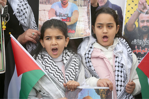 Palestinian children chant slogans while holding Palestinian flags during the solidarity vigil in front of the International Committee of the Red Cross in Nablus, West Bank. The vigil also served as a protest against the death penalty law approved by the Israeli cabinet.